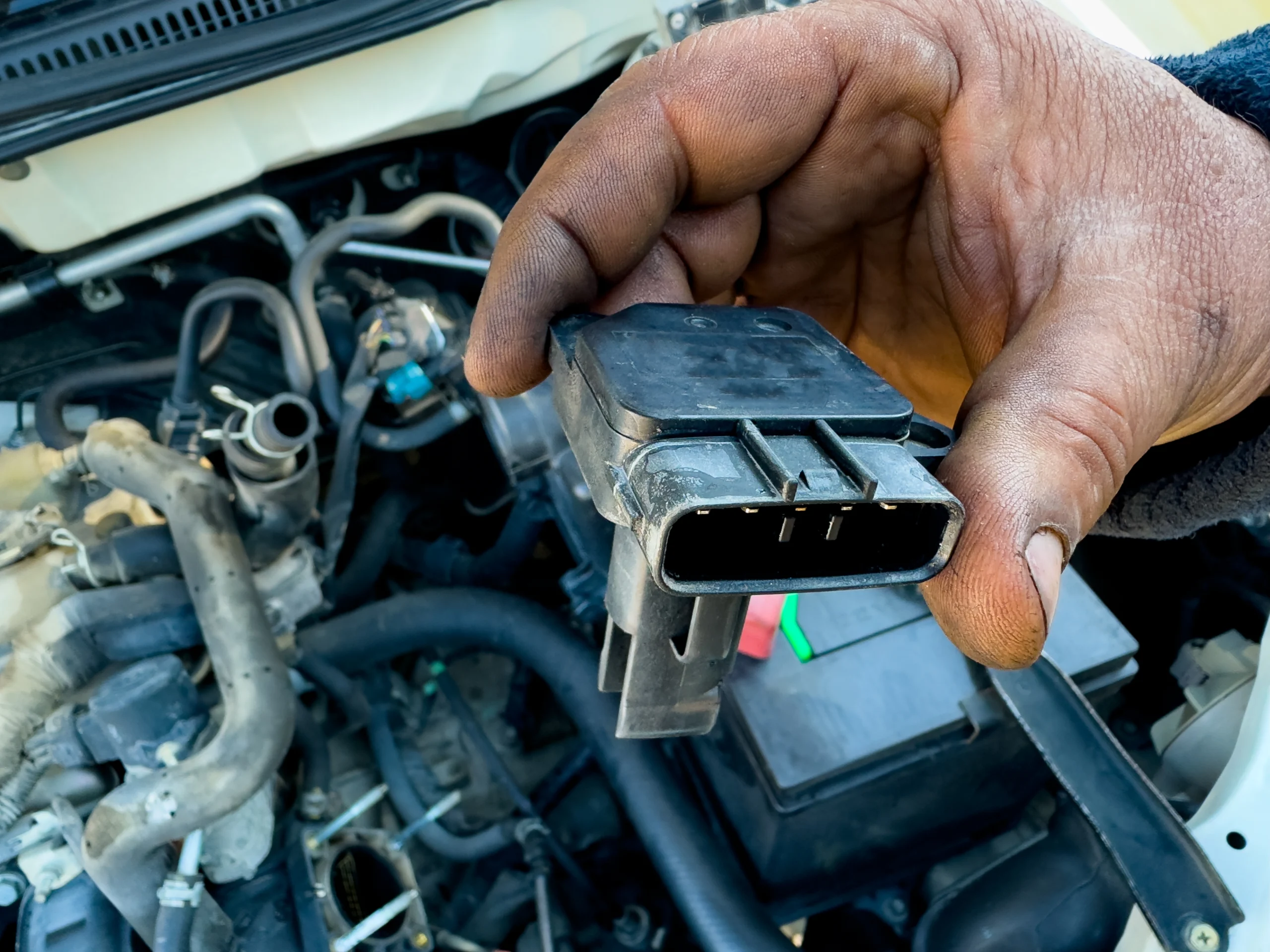Close-up of a coil-on-plug ignition coil being removed from an engine